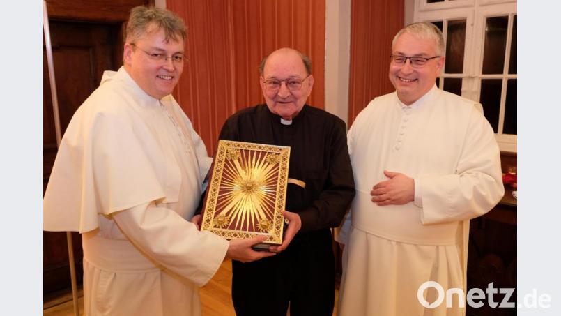Mit einem wertvollen Evangeliar als Schenkung für die Klosterbibliothek überrascht Bischöflich Geistlicher Rat Heribert Schmitt (Mitte) Abt Hermann Josef Kugler (rechts) und Prior Pater Adrian Kugler. Bild: do