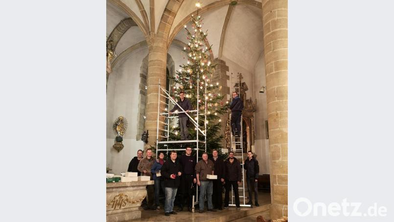 Eugen Zeitler, Florian Frank, Regina Frank, Markus Lehner, Michael Denz, Klaus Scherer, Pfarrer Thomas Kraus, Peter Ferner und Moritz Ferner (von links), sowie Lukas Häckl (Gerüst) und Andreas Gallei (Bockleiter) vor dem großen Christbaum in der Kemnather Stadtpfarrkirche. Bild: mde