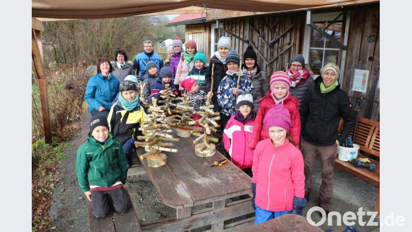 Stolz zeigen die Kinder ihre selbstgebastelten Birkenbäume. Katharina Hage (rechts) besorgte das Birkenreißig. Anton Kuchenreuther (hinten Mitte, zur Hälfte verdeckt) bereitete die Baumscheiben vor und half den Kindern beim Basteln. Bild: rpp