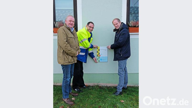 Bürgermeister Konrad Kiener, der Leiter des Wasserwirtschaftsamts Weiden Mathias Rosenmüller und Marktrat Dieter Rosenberg (von rechts) beim Anbringen der ersten Hochwassermarke am FC-Sportheim Bild: twi