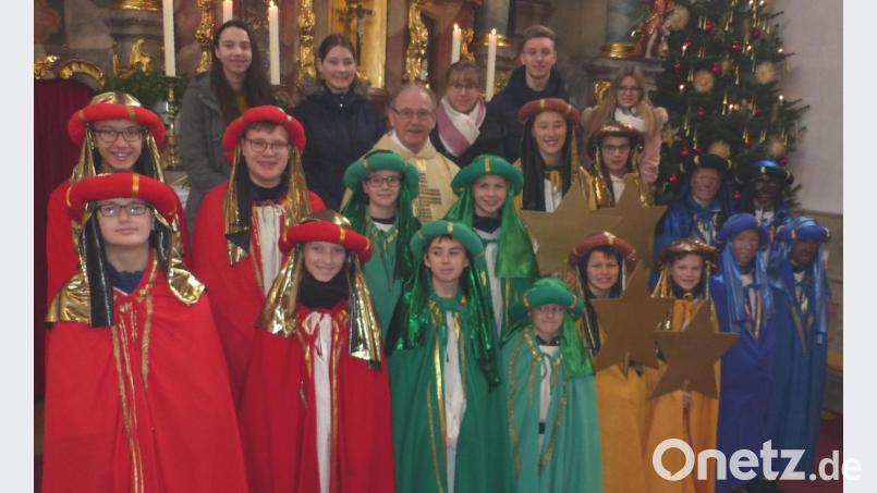 Pater Adrian Hamberger (Mitte) sendet die Sternsinger in die Pfarrei aus. Die 16 Mädchen und Buben werden auf ihrem Weg von älteren Ministranten begleitet (hintere Reihe). Bild: lgc