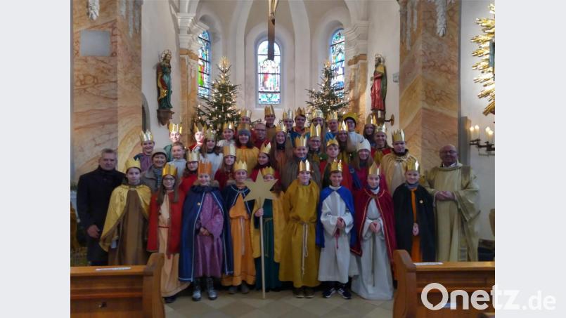 Die Sternsinger geben die Spenden im Gottesdienst am Dreikönigstag an Pfarrer Wilhelm Bauer (rechts) weiter. Bild: rfi