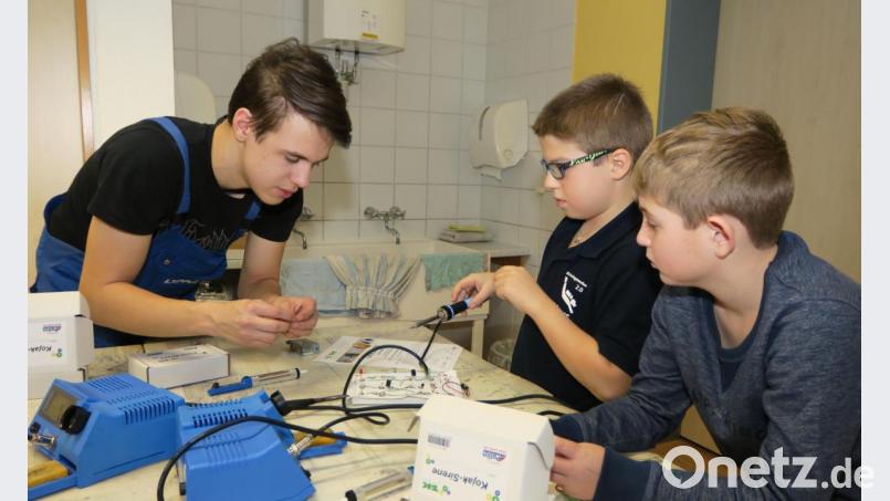 Auszubildende der Firma Läpple basteln und löten mit den Kindern und erläutern ihnen technische Zusammenhänge. Bild: Hirsch
