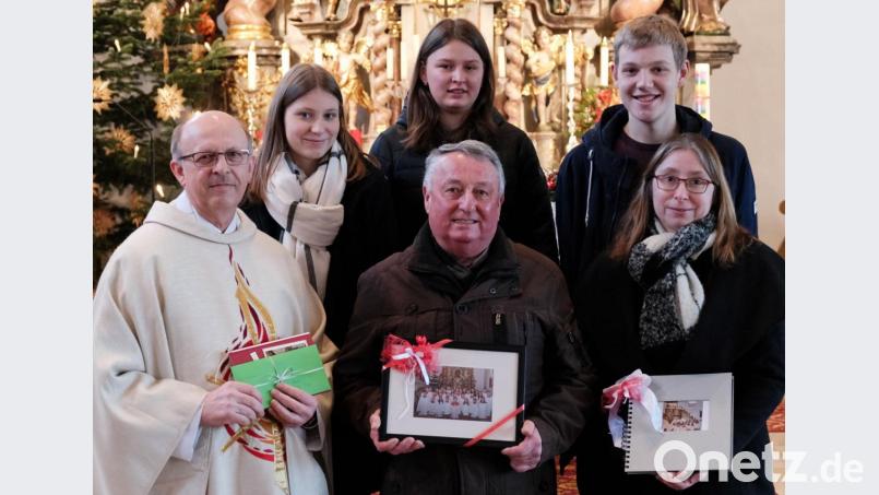 Pfarrer Herbert Rösl (links), die Oberministranten (hintere Reihe) und Nachfolgerin Christiane Hammer (rechts) verabschiedeten sich von Ministranten-Betreuer Josef Pflug . Als kleines Dankeschön gab es einen Gutschein, ein Einnerungsbild und ein Fotoalbum über die gemeinsame Zeit. Bild: tkr