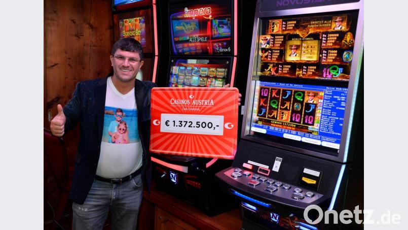 Gewinner Leon Tsoukernik steht mit einem symbolischen Scheck über die Gewinnsumme von 1,37 Millionen Euro neben Spielautomaten im Casino Seefeld. Bild: Casinos Austria/dpa