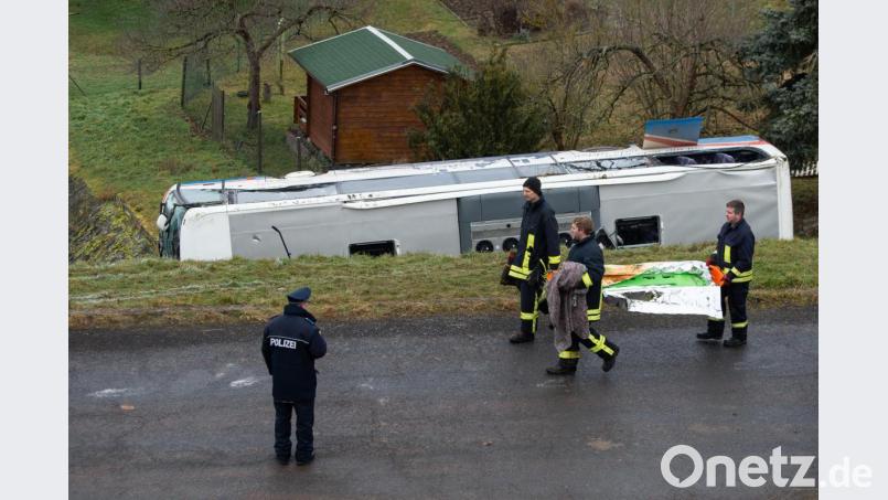 Einsatzkräfte gehen an dem verunglückten Schulbus vorbei. Bild: Swen Pförtner/dpa