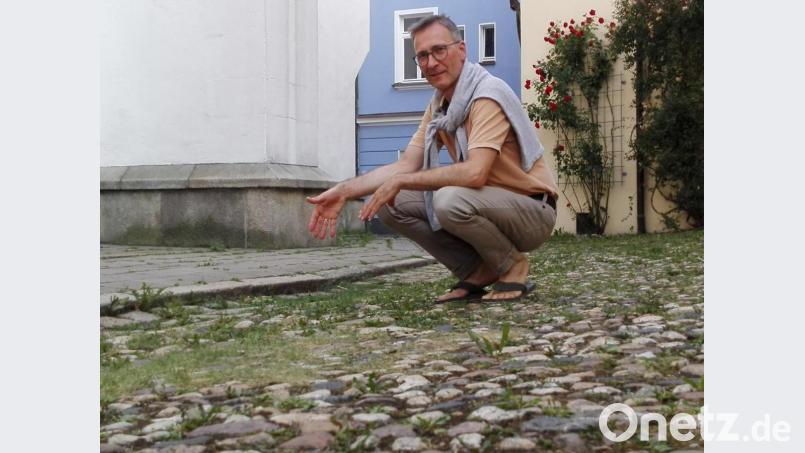 Pfarrer Hans-Martin Meuß zeigt auf eine der Absenkungen im Steinpflaster. Bild: Hladik