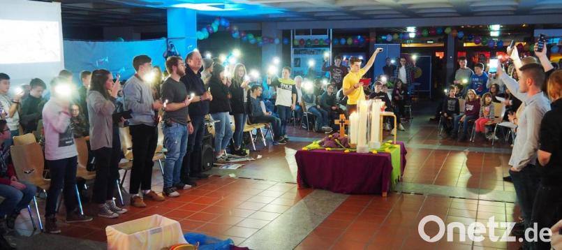 Plötzlich ist der Saal durch Handy-Lampen symbolisch erleuchtet. Bild: Bühner