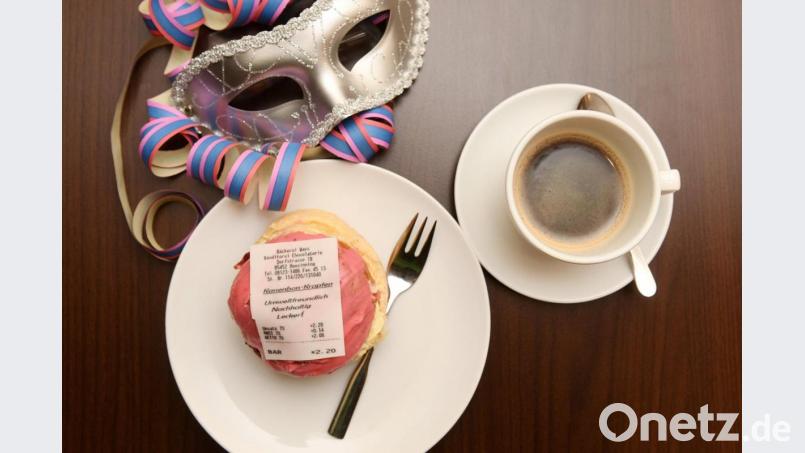 Ein Krapfen mit einem Kassenbon aus Fondant, einer essbaren Zuckermasse und eine Tasse Kaffee. Foto: Tobias Hase/dpa Bild: Tobias Hase