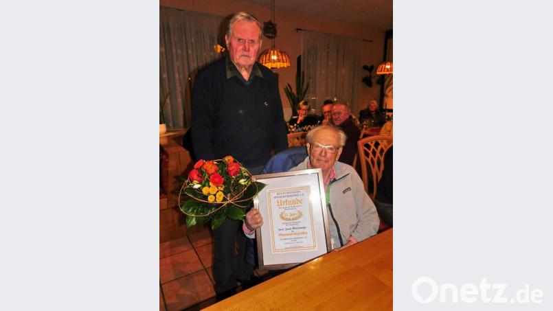 Josef Mittelmeyer (sitzend) erhielt vom Stellvertretenden Vorsitzenden Rudi Richter neben der Ernennungsurkunde zum Ehrenvorsitzenden auch einen Strauß Blumen. Bild: hai