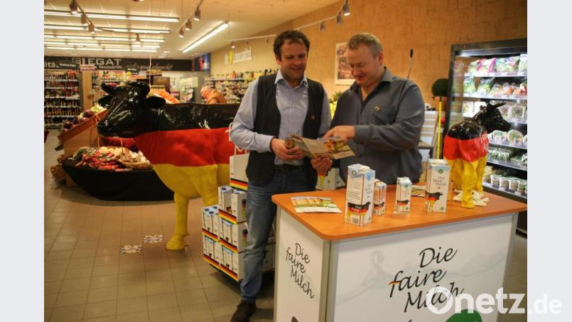 BDM-Kreisvorsitzender Werner Reinl (rechts) mit fairer Milch im Neustädter Edeka. Die Markenkommunikation befördert den Begriff „Die faire Milch“ zusammen mit einem schwarz-rot-goldenen Design. Dazu gehört das Maskottchen und Logo-Tier „Faironika“, eine schwarz-rot-golden gefärbte Kuh. Diese Kuh kam in der Vergangenheit als lebensgroße Plastikvariante bei Demonstrationen der Milchbauern zum Einsatz und wurde überregional bekannt. Bild: jrh