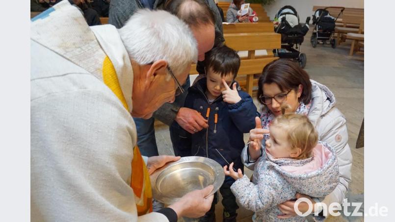 Pfarrer Josef Beer mit einer Familie, die sich gegenseitig mit Weihwasser bekreuzigte. Bild: wec
