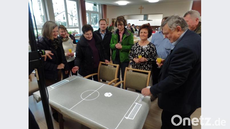 Eine sogenannte „Tovertafel“ projizierte ein Fußballfeld auf eine Tischplatte. Der Spielball reagierte auf kleinste Bewegungen, wovon sich Bürgermeister Manfred Porsch (rechts) selbst überzeugte. Tagespflege-Leiterin Maria Reiß (Zweite von rechts) sowie ihre Stellvertreterin Karina Volkmann (Zweite von links) schauten zu beim Versuch, den Ball ins Tor zu „schießen“. Bild: br