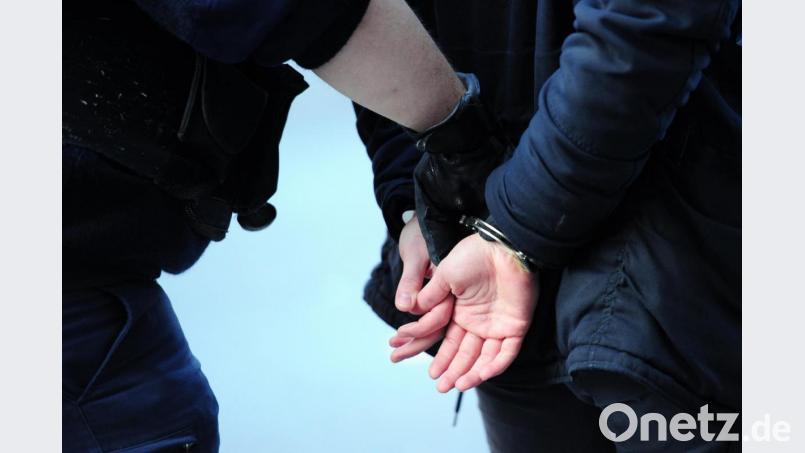 Polizisten führen einen in Handschellen gefesselten Mann ab. Grafik: Daniel Reinhardt/dpa