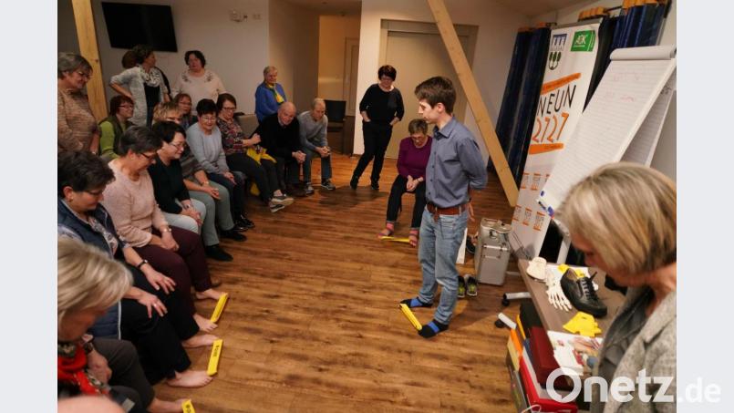 Schuhtechniker Horst Schedl (Mitte stehend) zeigt den Teilnehmern eine Übung mit dem Gummiband, die den Fußmuskels trainiert. Bild: fvo