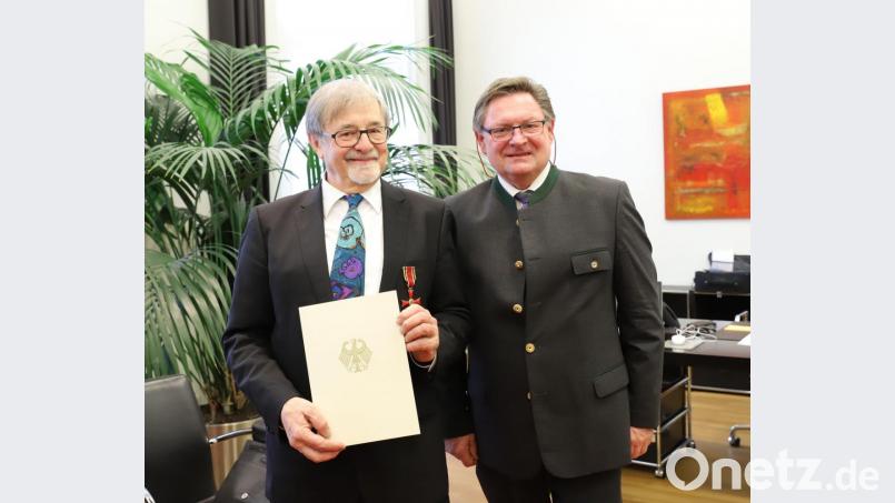 Innenstaatssekretär Gerhard Eck heftet Veit Wagner (links) das Bundesverdienstkreuz am Bande an. Bild: Bayerisches Innenministerium/exb
