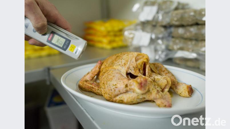 Ein Lebensmittelkontrolleur überprüft bei einer Betriebskontrolle die Temperatur eines Hähnchens. Bild: Uwe Anspach