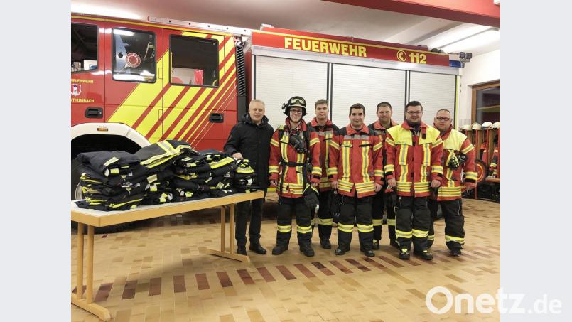 Bürgermeister Jürgen Kürzinger (links) übergibt im Gerätehaus die neuen Schutzhosen für die Feuerwehr. Bild: jma
