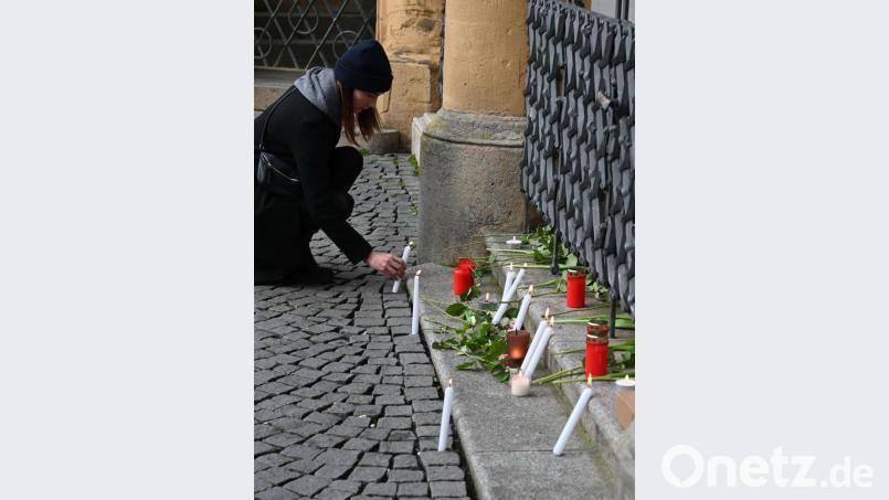 Eine junge Frau stellt eine brennende Kerze vor dem Rathaus auf. Bild: gf