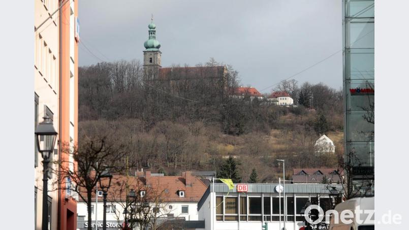 Der aktuelle Blick auf den Mariahilfberg von der Bahnhofstraße aus. Dass man selbst bei kahlen Bäumen die derzeit auf der Terrasse zusammengeschobenen großen Sonnenschirme nicht sehen kann, wertet Franz Mertel als Beweis, dass auch die vorgesehene Erweiterung des Gebäudes nach hinten, also in den Hang hinein, von unten kaum wahrzunehmen sein werde. Der Kirchenpfleger der Filialkirchenverwaltung Mariahilfberg hat dazu selbst eine Fotostrecke aus vielen unterschiedlichen Standpunkten in der Stadt angelegt. Bild: Wolfgang Steinbacher