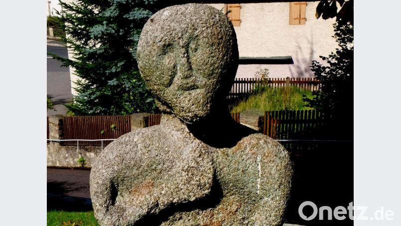 Die stark verwitterte, sitzende, aus Granit herausgearbeitete gnomenhafte Figur mit langen Armen, wobei die rechte Hand zur Beteuerung am Herzen liegt, ist eine der vielen Kulturdenkmäler im Flosser Amt. Im Rathausplatz hat sie seit l975 hoffentlich endgültig, ihren festen Platz gefunden. Bild: le