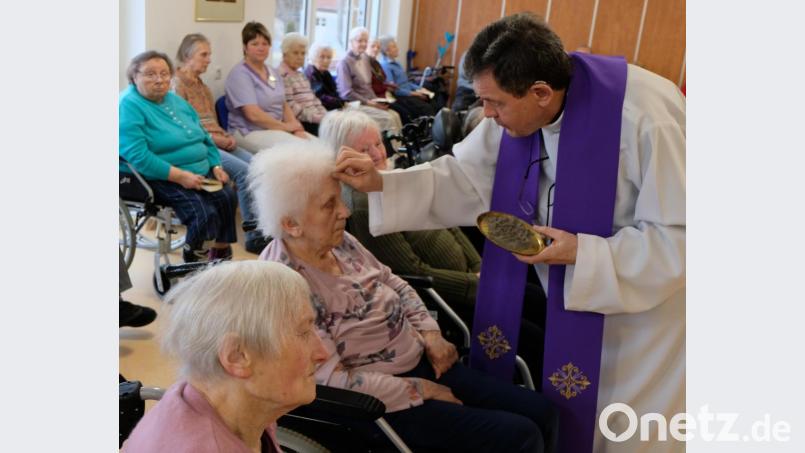 Pfarrer Max Früchtl zeichnet das Aschenkreuz auf die Stirn der Messebesucher. Bild: le