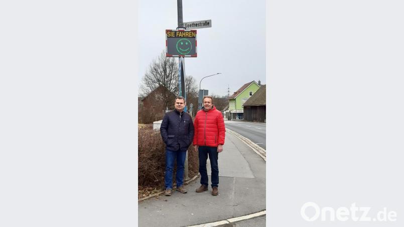 Ein neues Geschwindigkeitsmessgerät soll die Autofahrer vor der Grund- und Mittelschule daran erinnern, etwas langsamer zu fahren. Bürgermeister Karlheinz Budnik und Stadtrat Werner Sauer freuen sich über den grünen Smiley, der immer dann zu sehen ist, wenn die Autos langsam fahren. Bild: Lowak