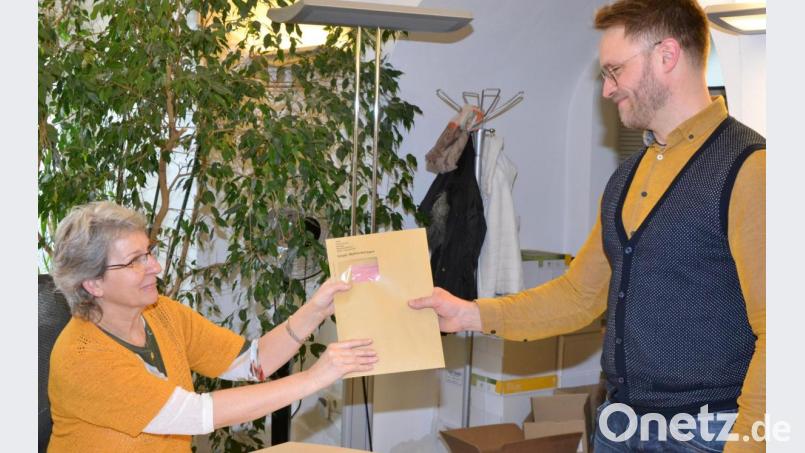 Erna Zandt-Rumrich (links) übergibt einem Bürger einen braunen Umschlag. Darin befinden sich die Briefwahlunterlagen. Bild: sfo