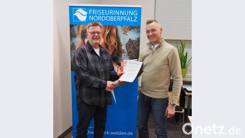 Alfons Kliebhahn, Obermeister der Friseur-Innung Noroberpfalz (links), überreicht seinem Vorgänger Harald Raml die Ernennungsurkunde zum Ehrenobermeister. Bild: Bühner