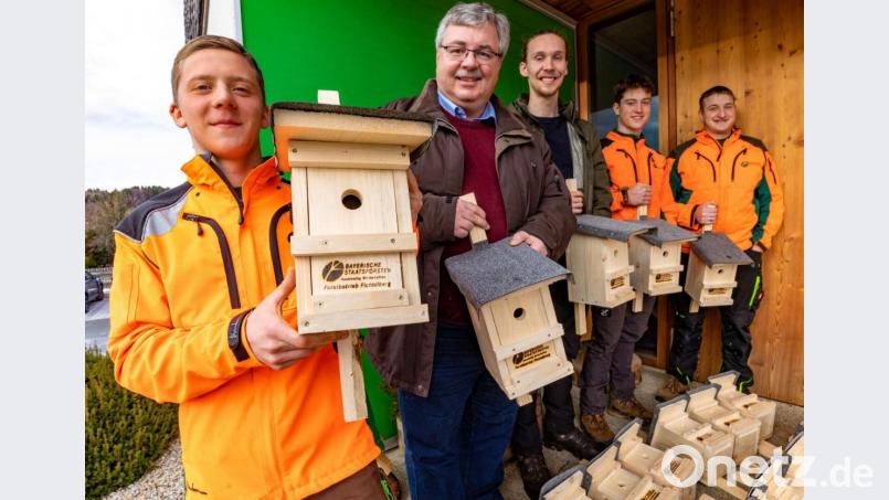 Sozialer Wohnungsbau für Singvögel: Jonas Plessgott (links), Ulli Stöhr und Korbinian Scherm (rechts) präsentieren die Vogelnistkästen, die sie für ein Forschungsprojekt der Universität Bayreuth an Robert Pfeifer und Lucas Fäth übergeben. Bild: Martin Hertel/exb