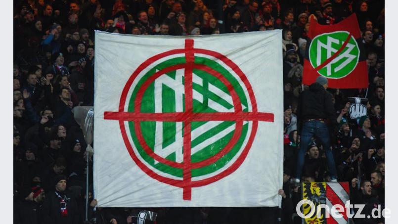 Nürnberger Fans halten am Freitagabend ein Banner mit dem Logo des DFB in die Höhe, das in einem Fadenkreuz zu sehen ist. Bild: Nicolas Armer/dpa