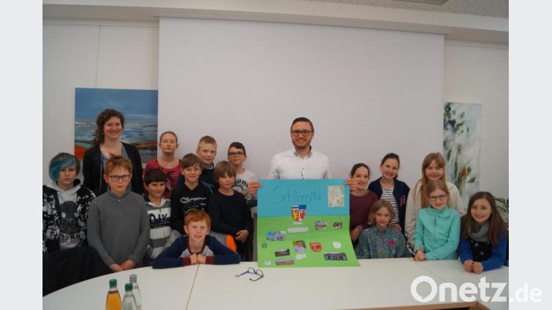 Die 16 Kinder der vierten Grundschulklasse mit Fachlehrerin Anna Reissinger (hinten, links) haben an Bürgermeister Ernst Lenk (Mitte) viele Fragen. Am Schluss überreichen sie ihm eine Bildtafel über Schirmitz. Bild: du