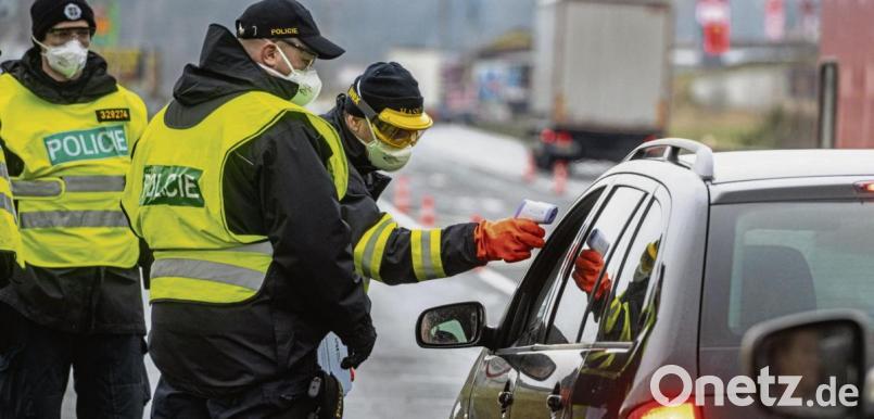 Ein Feuerwehrmann aus Tschechien misst neben Polizisten die Temperatur von einem Einreisenden an der Grenze bei Ceska Kubice bei Furth im Wald. Bild: A. Weigel/dpa