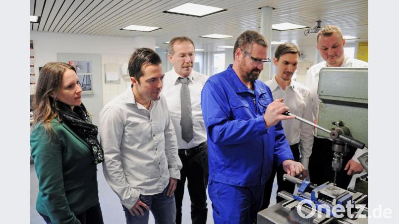 Allan Thompson zeigt am Standbohrer (von links) Stefanie Bauer (Teamleiterin Arbeitsvermittlung Amberg), Matthias Wiesnet (Arbeitsvermittler), Wolfgang Eichenseer (Geschäftsführer der Maxhütte Technologie), Michael Plödt (Kaufmännischer Leiter der Maxhütte Technologie) und Martin Sperber (Leiter des Berufsbildungszentrums), wie Werkstücke bearbeitet werden. Bild: Andre Stephan-Park/exb