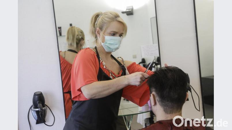 Eine Friseurin mit Mundschutz schneidet einem Kunden in Brüssel die Haare. Die Menschen in Belgien sollen 19 Tage lang zu Hause bleiben, um eine weitere Verbreitung des Coronavirus zu vermeiden. Der Friseursalon kann jeweils nur mit einem Kunden geöffnet bleiben. In Bayern bleibt es bislang den Friseuren selbst überlassen, ob sie ihren Salon öffnen oder nicht. Bild: Thierry Roge/BELGA/dpa