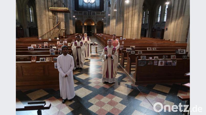 Ohne Menschen und doch im Kreise der Gläubigen: Arnald Francis (links) hatte die Idee Bilder von Gläubigen in der Weidener Josefskirche aufzustellen. Kaplan Pater Johannes Ernstberger (von rechts) und Stadtpfarrer Markus Schmid griffen diese Idee gerne auf. Bild: Würth, Wolfgang