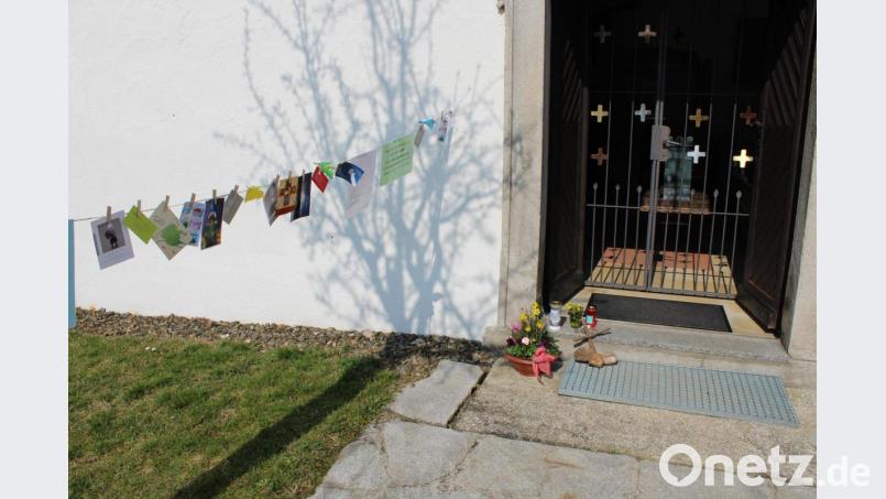 An Wäscheleinen vor den evangelischen Kirchen hängen Bilder und Gebete. Gemeindeglieder haben angefangen die Stationen mit Kerzen, Blumen und Postkarten zu erweitern. Bild: szl