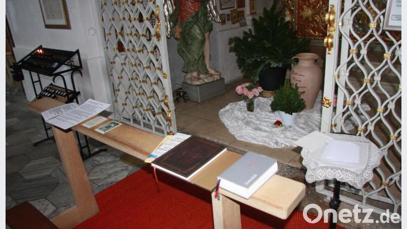 Vor dem Marienaltar liegen Gebetsbücher, Fürbitten und Andachtsbilder auf. Zudem findet man dort ein kleines Buch und (rechts auf dem Tischchen) Zettel, um Anliegen aufzuschreiben. Aufbewahrt werden sie in einem Krug, der hinter dem Gitter steht. Bild: wro