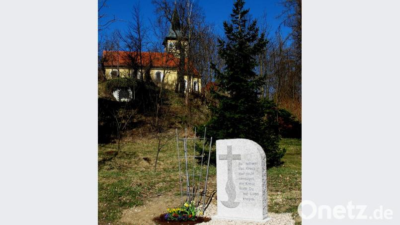 Der Gedenkstein zu Beginn der 14 Kreuzwegstationen zeigt einen Weg aus der Krise. Im Hintergrund steht das Kleinod des Marktes, die St. Nikolauskirche. Bild: le