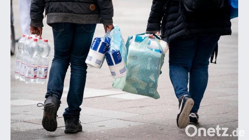 Passanten tragen Toilettenpapier, Wasser und weitere Einkäufe. Bild: Kay Nietfeld/dpa