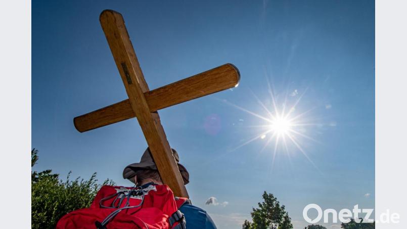 Ein Pilger trägt während der größten Fußwallfahrt Deutschlands ein Holzkreuz: Heuer fällt die Regensburger Diözesanfußwallfahrt nach Regensburg aus. Bild: Armin Weigel/dpa