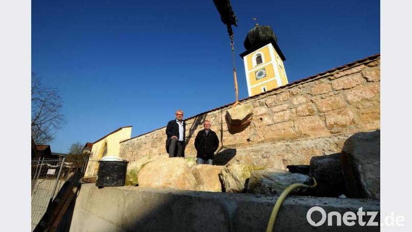 Die Sanierung der alten Friedhofsmauer, die den südlichen Teil des Geländes um die evangelische St.-Michaels-Kirche zum künftigen Dorfplatz abgrenzt, hat begonnen. Bürgermeister Roger Hoffmann (links) und Hartmut Gawlik (rechts), der geschäftsleitende Beamte der Gemeinde machten sich vor Ort ein Bild. Bild: Stephan Huber