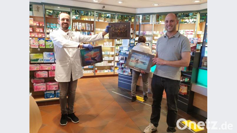 Den gebührenden Abstand einhaltend präsentieren Jens Simon und Apotheker Ralph Bauer die Puzzle, die es für Familien gratis gibt. Bild: adj