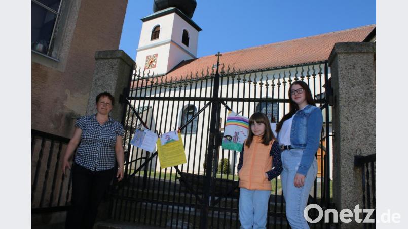 Wenn schon kein Ostergottesdienst stattfinden soll, kann man zumindest Botschaften am Kirchengatter hinterlassen. Corinna Pfeiffer, Anastasiia und Elena machen es vor. Bild: sne