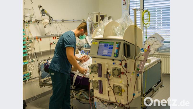 Ein Pfleger kümmert sich um einen Patienten, der während seines Aufenthalt im Krankenhaus in einem Intensivzimmer an einem Beatmungsgerät und einem Dialysegerät hängt. Bild: Peter Kneffel/dpa