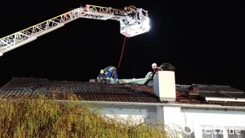 Mit Hilfe der Drehleiter dichten Männer von THW und Feuerwehr das schwer beschädigte Dach ab. Bild: exb/Jan Braunreiter (THW)