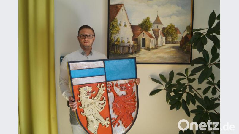 In dankbarer Erinnerung an den verstorbenen Holzbildhauer Wendelin Sperl, der auch in Schirmitz elf Jahre lang wirkte, zeigt Bürgermeister Ernst Lenk mit dem farbigen Gemeindewappen und dem Holzrelief von Alt-Schirmitz zwei Meisterwerke des Künstlers. Bild: du