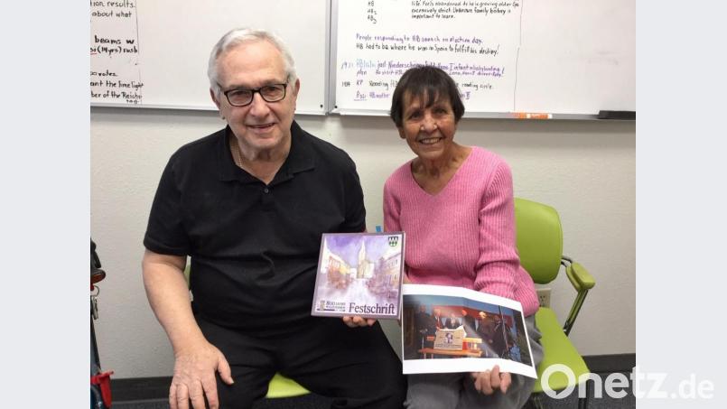 Hans Anthony Beimler (links), der amerikanische Enkel des in Waldthurn aufgewachsenen Freiheitskämpfer Hans Beimler hält Ende Februar 2020 die übersandte Festschrift &quot;800 Jahre Waldthurn&quot; in seinen Händen. Dort ist das Leben seines Großvaters nachgezeichnet. Seine Kollegin Georgette Weihrauch freut sich über das Bild von der Enthüllung der Hans-Beimler-Gedenktafel in Waldthurn. Bild: fvo