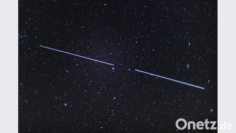 Zwei „Starlink“-Satelliten sind als Lichtstreifen am Nachthimmel zu sehen. Bild: Patrick Pleul/dpa