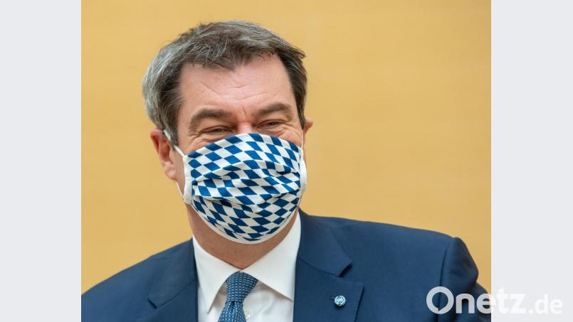 München: Markus Söder (CSU), Ministerpräsident von Bayern, zieht sich für die Fotografen vor Beginn der Sitzung des bayerischen Landtags eine Mundschutzmaske auf. Bild: Peter Kneffel/dpa
